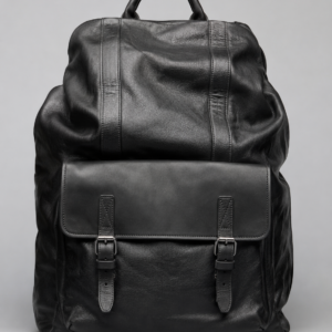 Premium black leather backpack with front flap pocket, buckle straps, and soft genuine leather texture on a light grey studio background.